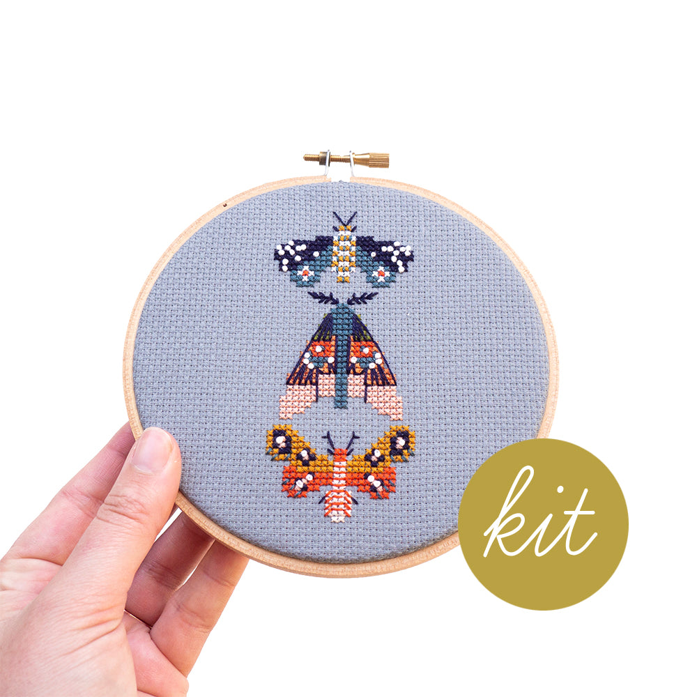 three very colorful moths on blue aida cloth, DIY cross stitch kit