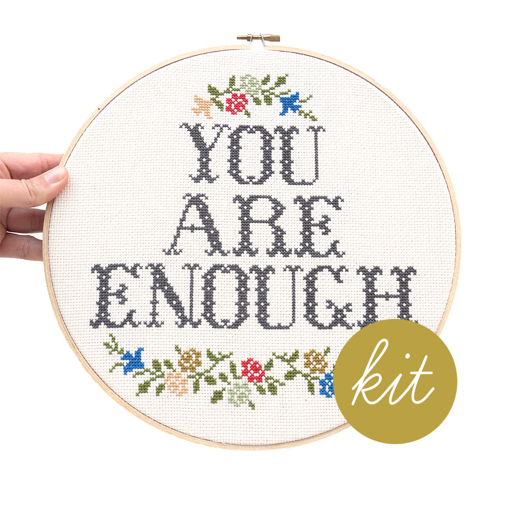 large font reads You Are Enough with multiple color flowers on top and bottom of text, DIY cross stitch kit